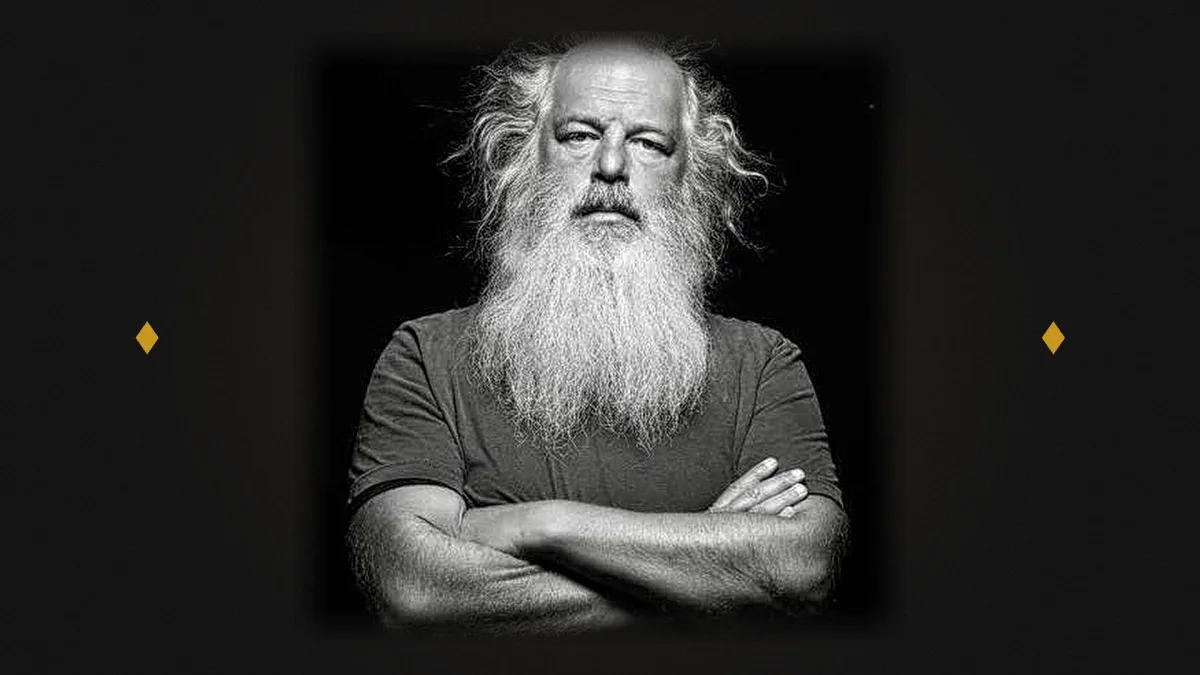 Ritratto in bianco e nero di Rick Rubin a braccia incrociate su fondo nero